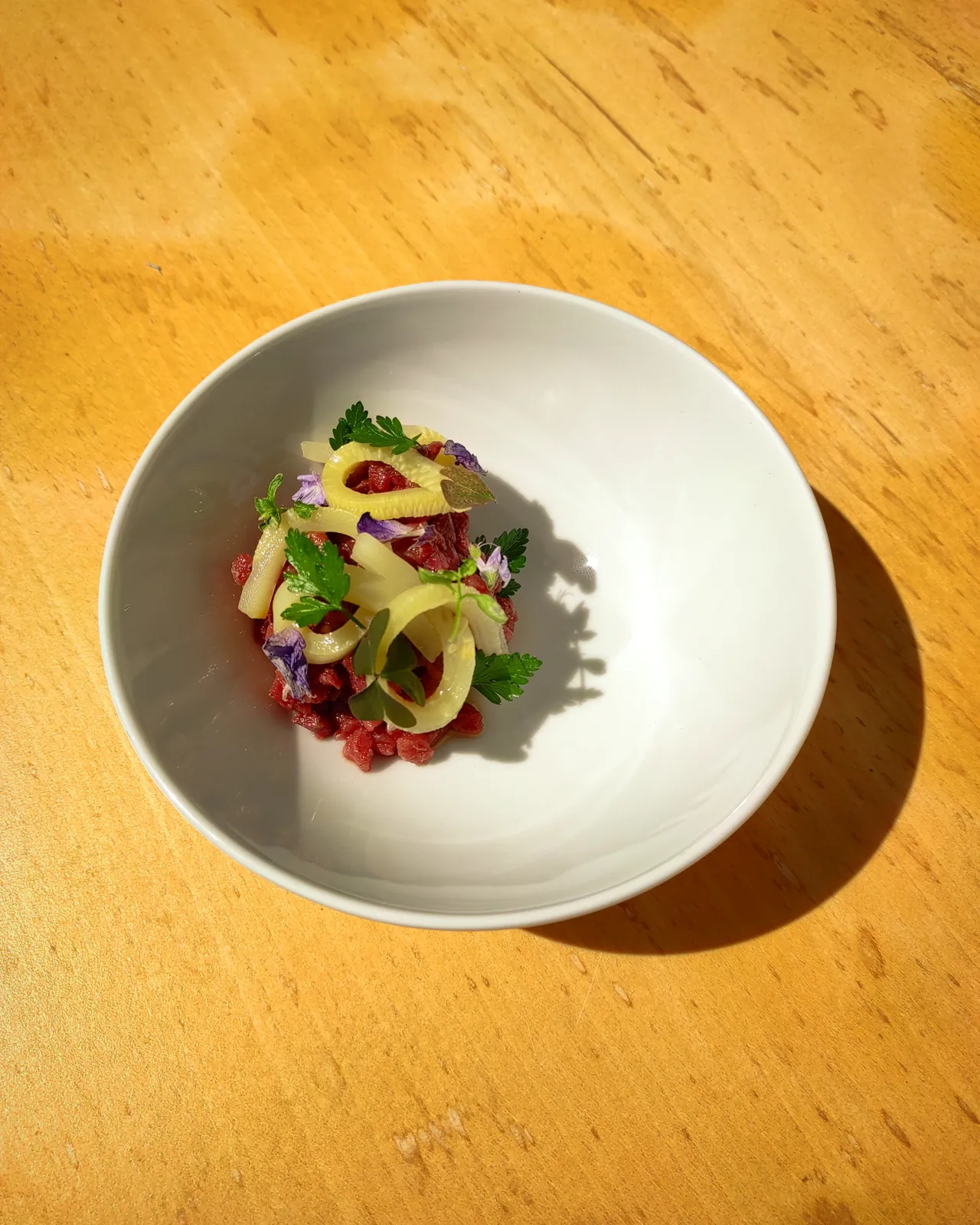 Wild boar tartare with pickles and wild flowers, plated by Dwyght Vester